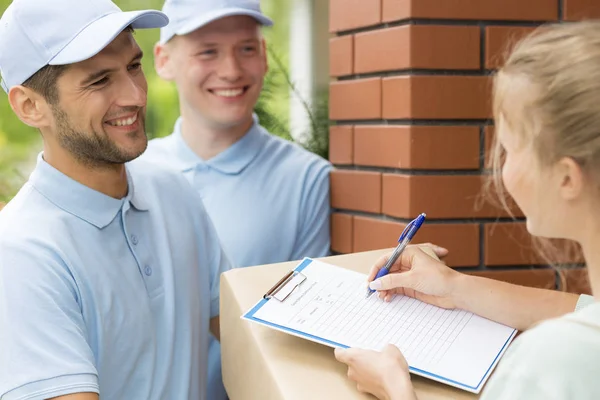 Smiling Friendly Couriers Blue Uniforms Woman Signing Receipt Package Delivery — Stock Photo, Image
