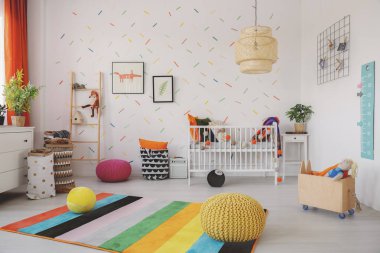 Poufs SCANDI bebeğin oda iç beşiği ve duvar kağıdı posterleri ile renkli halı üzerinde. Gerçek fotoğraf