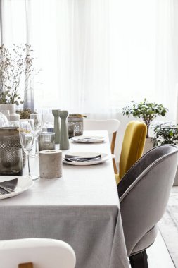 Tablo parlak yemek odası iç pencere perdeleri ile yemek, mum ve gri ve sarı koltuğu konumu olan gerçek fotoğraf