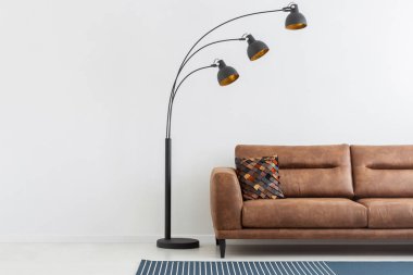 Lamba yanında kahverengi deri kanepe beyaz düz iç kopya alanı boş duvar ile. Gerçek fotoğraf