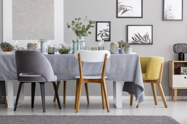 现代椅子在桌子上与餐具在灰色的餐厅内部与海报和植物 真实照片 — 图库照片
