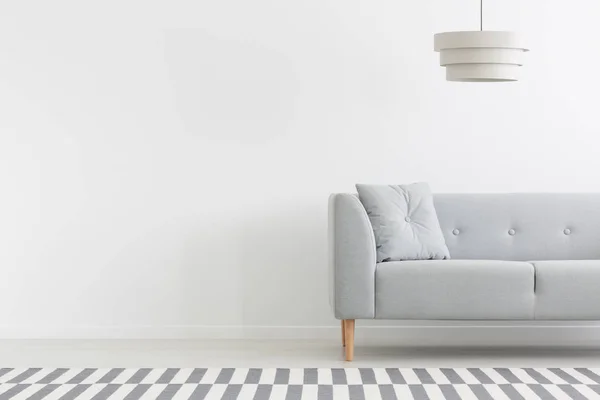 空の壁にコピー スペースを持つ白い最小限アパート インテリアでグレーのソファ上ランプ 実際の写真 — ストック写真