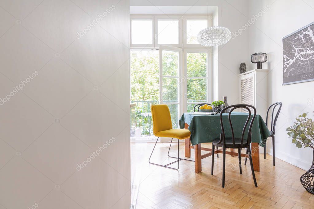 Living room interior with long table with green table cloth and different kind of chairs, black map on the wall, real photo with copy space