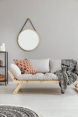 Mockup boho düz iç desenli battaniye ile gri kanepe üzerinde yuvarlak ayna. Gerçek fotoğraf