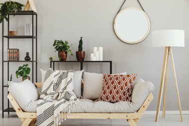 Desenli yastık ve battaniye zarif salon iç bej Duvar ile şık İskandinav kanepenin yanındaki beyaz ahşap lamba