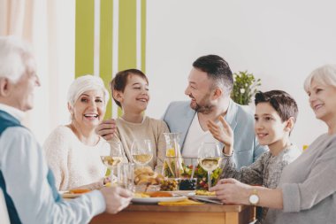 Gülümseyen Büyükanne ile aile akşam yemeği sırasında veliler arasında mutlu çocuk