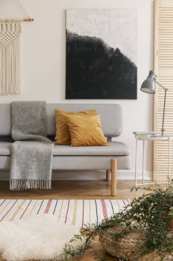 Poster kanepe kahverengi minderler ve boho oturma odası iç lamba ile gri battaniye ile yukarıda. Gerçek fotoğraf