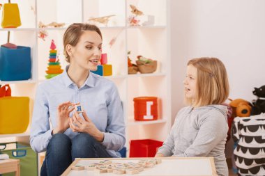 Kız okulda konuşma terapisti ile sınıf sırasında alfabesi öğrenme