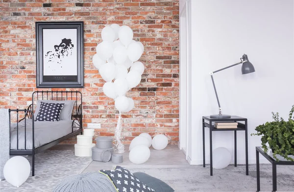 Map in black frame on the brick wall in elegant scandinavian bedroom with bunch of white balloons