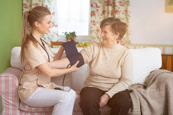 Uśmiechający Się Pielęgniarka Pomiar Ciśnienia Szczęśliwy Senior Kobiety Domu — Zdjęcie stockowe