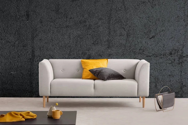 テクスチャ壁とテーブルのリビング ルームのインテリアのグレーのソファーに黄色と黒の枕 実際の写真 — ストック写真