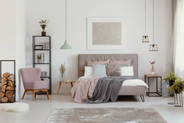 Pembe tekli yanındaki gri yatak yatak odası iç poster ve bitkiler ile battaniye ile. Gerçek fotoğraf