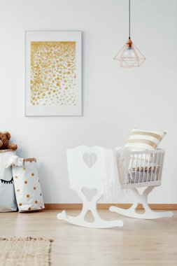 Parlak bebek çocuk beyaz beşik ve boş beyaz duvardaki altın boyama ile dikey görünüm