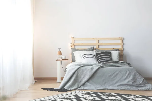 Gedessineerde Kussens Grijs Houten Bed Eenvoudige Slaapkamer Interieur Met Lamp — Stockfoto