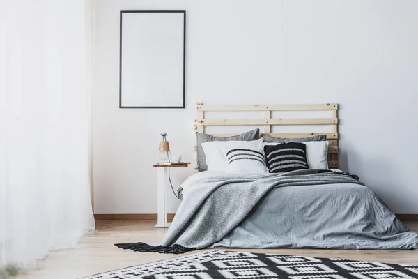 灰色の木製ベッド クッション付け白い寝室のインテリアで空ポスターのモックアップ 実際の写真 — ストック写真