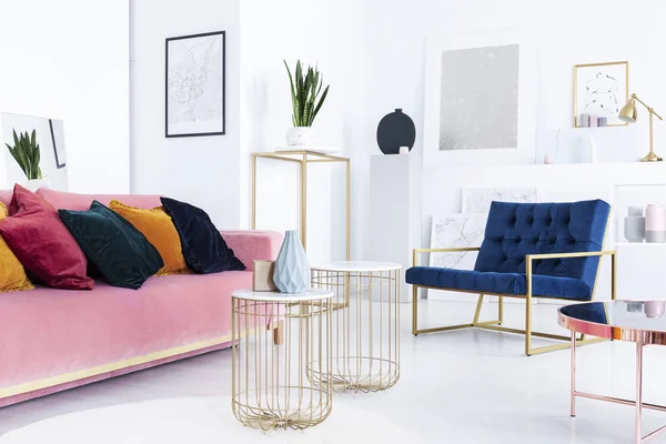 真正的照片金色的桌子 粉红色的沙发枕头和蓝色扶手椅在明亮的客厅内部 — 图库照片