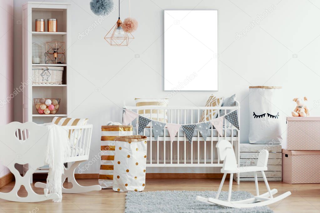 Empty mockup poster on the wall of interior with white wooden rocking horse, crib and nursery with white and gold accents, real photo