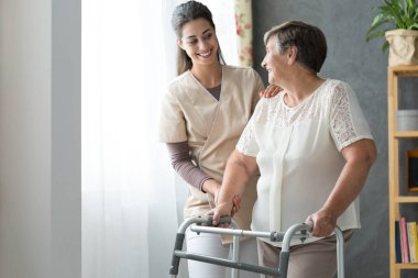 Gülümseyen güzel caregiver ve Engelli yaşlı kadın evde Walker