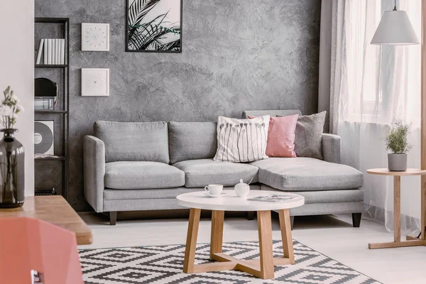 枕とグレーのソファで流行の居間で模様の敷物の上に円形のコーヒー テーブル — ストック写真