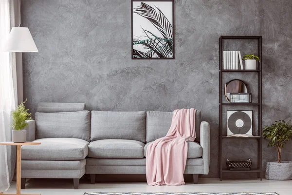 柔和的粉红色毯子在灰色舒适的沙发上 在当代客厅与工业黑色书架 — 图库照片