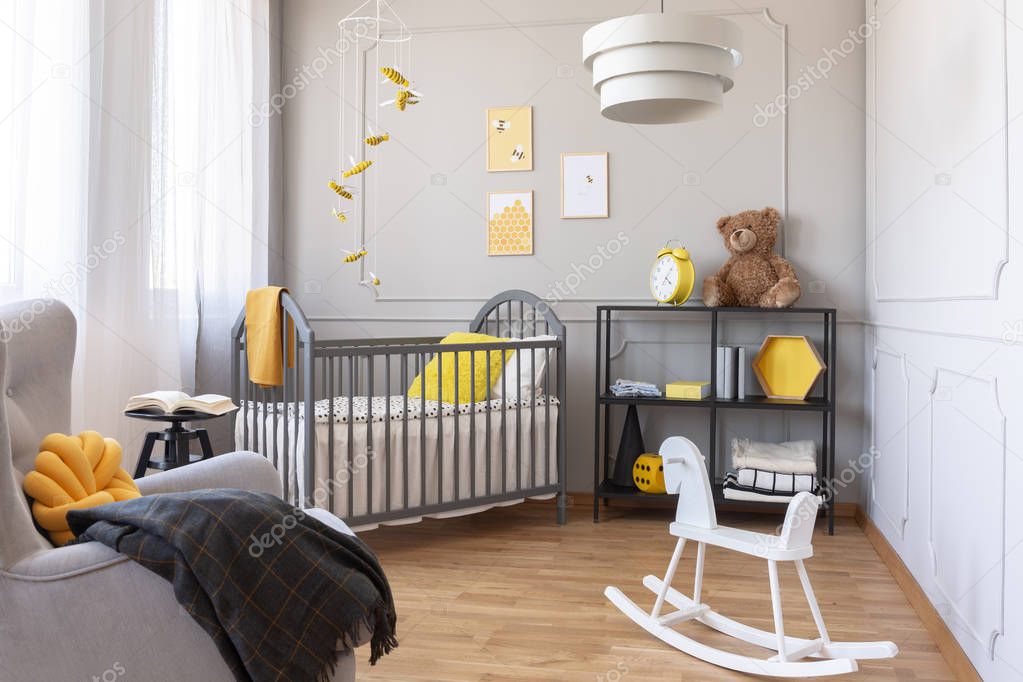 White rocking horse in elegant baby nursery with grey wooden crib and yellow accents