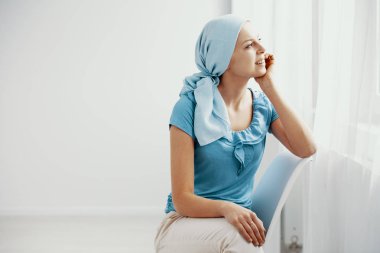 Lupus acı, mavi başörtüsü giyen ve hastanede pencereden bakarak Genç kız gülümseyerek, alan boş duvara kopyalama