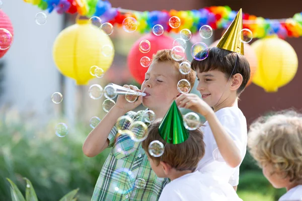 Gelukkige Jongens Met Kleurrijke Hoeden Zeepbellen Maken Tijdens Buiten Verjaardagsfeestje — Stockfoto