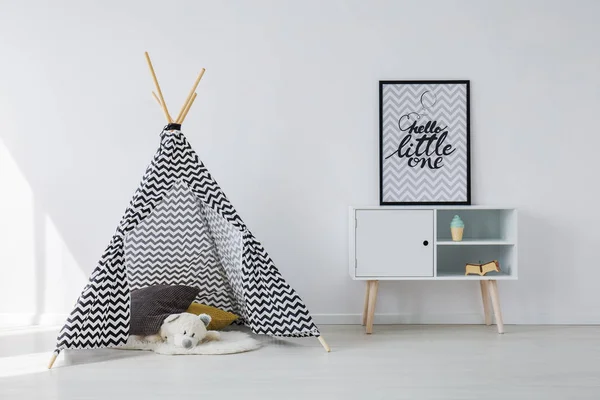 黑色和白色的斯堪的纳维亚帐篷与灰色和黄色的枕头和白色的泰迪熊旁边的木制柜子与海报在黑色的框架 复制空间在空的白色墙壁 — 图库照片