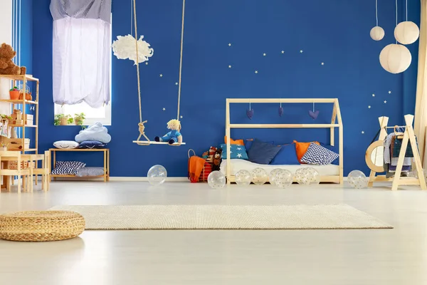 蓝色的墙壁与金色的星星在别致的斯堪的纳维亚儿童房间与枕头和玩具木床 — 图库照片
