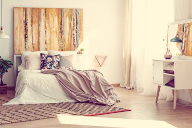 Çiçek yastık ve duvardaki soyut resim ile şık yatak odası iç rahat yatak üzerinde pastel pembe levhalar