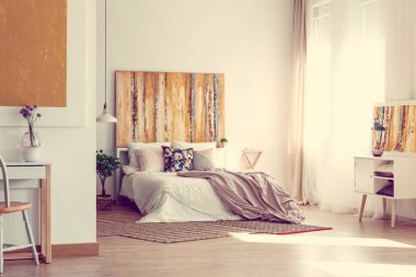 Çağdaş yatak odası iç duvarda süslü resim ve ahşap zemin üzerinde doğal halı ile yatakta çiçek yastık ve Kral üzerine pastel pembe yaprak boyutu