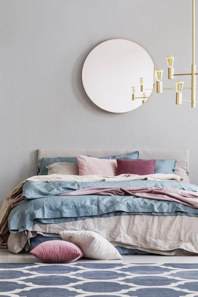 ひよこラウンド ブルー パステル ピンク ベージュの寝具と暖かいベッドでエレガントな寝室のインテリアに灰色の空のコピー スペースの壁に鏡 — ストック写真