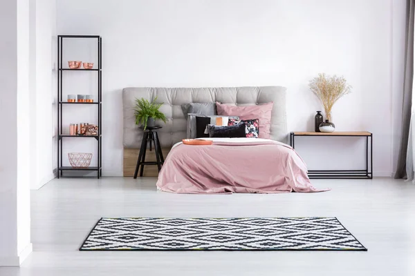 现代卧室内部地板上的黑色和白色地毯 配有舒适的床 床头板 柔和的粉色床上用品和工业家具 — 图库照片