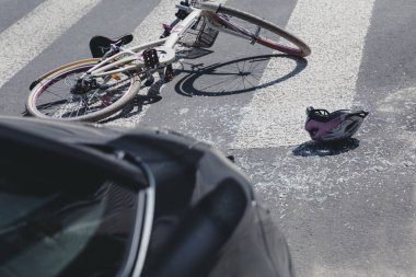 Helmet and bicycle on a crosswalk after collision with a car clipart
