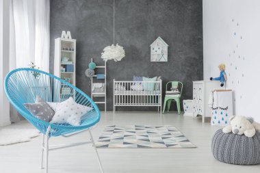 Kabarık üzerinde peluş oyuncak ile yıldız yastık mavi koltukta gri bebeğin yatak odası iç, üzerinde. Gerçek fotoğraf