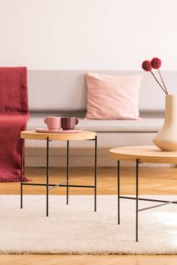 Kahve masa kahve fincanı ve aydınlık oturma odası iç gri kanepe ile gerçek fotoğraf kopya alanı boş beyaz duvar ile çiçekli vazo