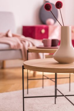 Yuvarlak ahşap masa oturma odası iç ile halı üzerinde beyaz Vazoda Kırmızı çiçekler. Gerçek fotoğraf