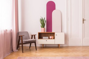 Beyaz ve pembe salon iç fabrikasında dolapla yanındaki gri ahşap tekli. Gerçek fotoğraf