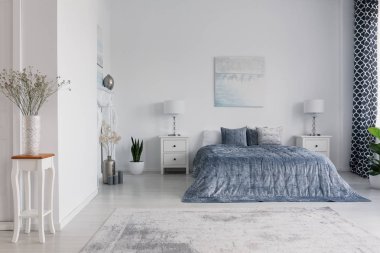 Masa ve dolapları mavi yatak yukarıda posteri ile beyaz yatak odası iç lambalar bitki. Gerçek fotoğraf