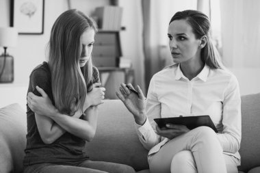 Black and white photo of professional pedagogue relieving stress of young teenage girl during psychotherapy. Mental health concept. clipart
