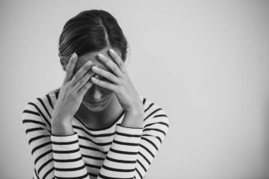 Black and white photo of young hopeless woman suffering from depression and holding her head, photo with copy space clipart