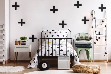 Siyah beyaz duvar ve konforlu yatak odası iç tek metal yatak ve nane gri sandalye yatak üzerinde haçlar