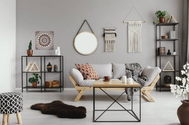 Sıcak etno oturma odası desenli yastık ve battaniye rahat İskandinav kanepede, gerçek bir fotoğraf ile ortasında şık ahşap sehpa