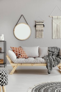 Makrome ve yuvarlak ayna gri desenli yastık ve battaniye, gerçek bir fotoğraf ile bej kanepe ile şık oturma odası