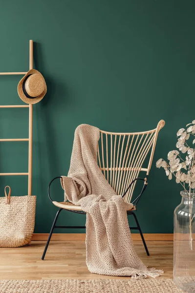 柳条扶手椅与米色毯子和木制梯子与柳条帽子 真正的照片与复制空间在空的绿色墙壁 — 图库照片