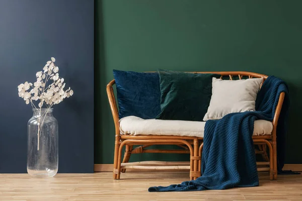 蓝色毯子和枕头上藤条沙发旁边的白色花朵在绿色的公寓内部 真实照片 — 图库照片