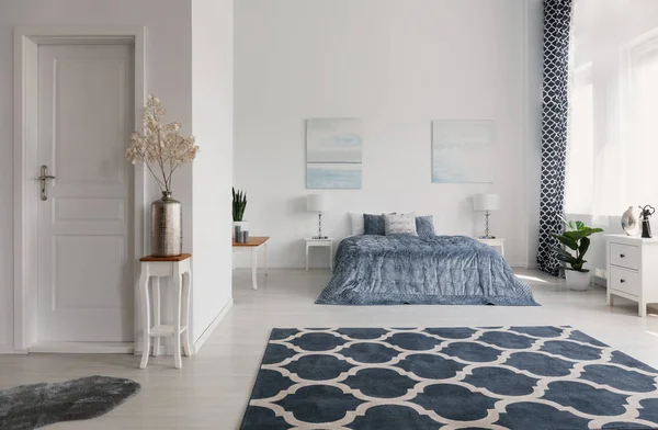 Desenli halı ferah yatak odası iç tablo ve posterler yatak yukarıda bitki ile. Gerçek fotoğraf