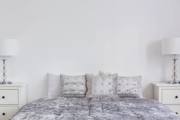 グレー ベルベット羽毛布団や枕快適なベッド 空の白い壁にコピー スペースを持つ本物の写真の上のクローズ アップ — ストック写真