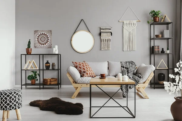 Sıcak etno oturma odası desenli yastık ve battaniye rahat İskandinav kanepede, gerçek bir fotoğraf ile ortasında şık ahşap sehpa