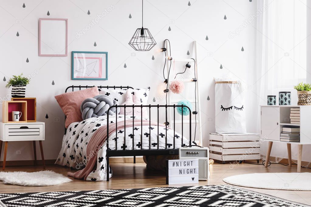 Black and white patterned carpet on wooden floor in stylish kid's bedroom interior with scandinavian design